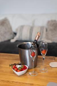 a table with two wine glasses and a bowl of strawberries at The Amazing Attic Apartment in Skipton