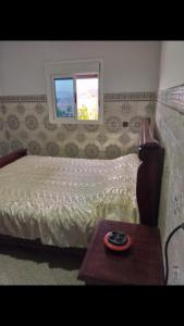 a bedroom with a bed with a table and a window at Appartement à ALHOCEIMA in Al Hoceïma