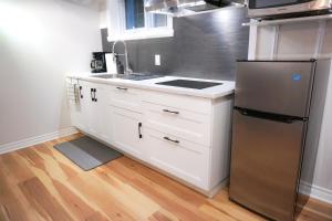cocina con armarios blancos y nevera de acero inoxidable en Cozy apartment in Ahuntsic with Free Parking and near metro station en Montreal