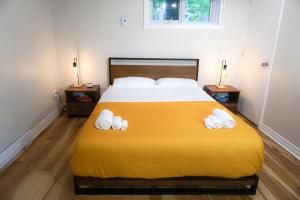 Un dormitorio con una gran cama amarilla con toallas. en Cozy apartment in Ahuntsic with Free Parking and near metro station en Montreal