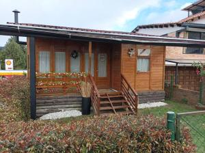 Cette petite maison en bois dispose d'une terrasse couverte et d'escaliers. dans l'établissement Beautiful Chalet In Bogota!, à Bogotá