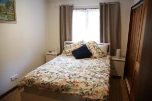 Un dormitorio con una cama con una almohada azul. en A Holiday Home for Every Season en Bateau Bay