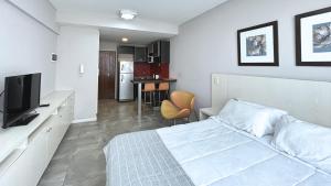 a bedroom with a bed and a tv and a kitchen at Marais Recoleta in Buenos Aires