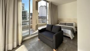 a bedroom with a bed and a chair next to a window at Marais Recoleta in Buenos Aires