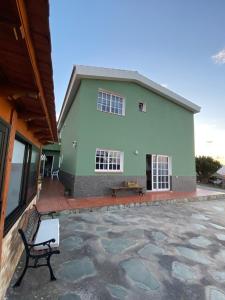 a green building with a bench in front of it at CASITA LAS VISTAS in Frontera