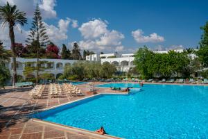 une grande piscine avec des chaises et un bâtiment dans l'établissement Le Hammamet Hotel & SPA, à Hammamet