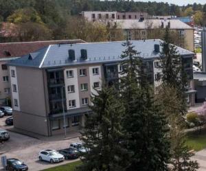 a large building with cars parked in a parking lot at Alyvų tako studija in Alytus