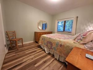 een slaapkamer met een bed, een stoel en een spiegel bij Hidden Oasis Close to Beach and Town in South Haven