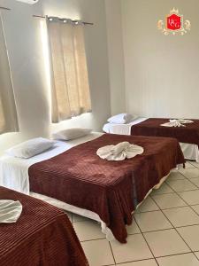 a hotel room with two beds with brown blankets at Hotel central campo grande in Campo Grande