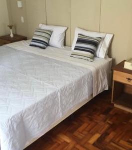 uma grande cama branca com almofadas em cima em Hospedaria das Brotas em Espírito Santo do Pinhal