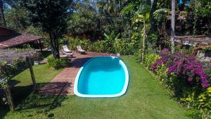 a blue swimming pool in a yard with flowers at Pousada casa zaza in Itacaré