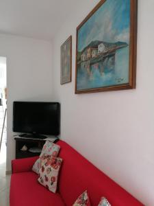 uma sala de estar com um sofá vermelho e uma televisão em Lemon House em Sassari