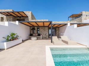 an outdoor patio with a swimming pool and a house at Villa Evi & Suites in Mikonos
