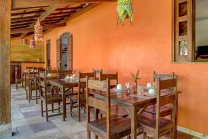 uma sala de jantar com mesas e cadeiras de madeira em Pousada casa zaza em Itacaré