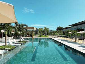 een zwembad met stoelen en parasols in een resort bij Flat Île de Pipa Luxxor - By Almare in Pipa