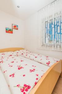 ein Bett mit einer weißen Decke mit roten Blumen drauf in der Unterkunft Apartment in Crikvenica with sea view, terrace, air conditioning, WiFi 3492-8 in Crikvenica