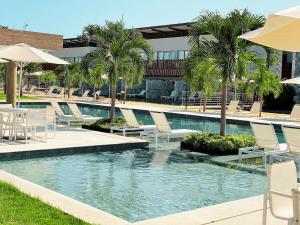 uma piscina com espreguiçadeiras e palmeiras em Flat Île de Pipa Varanda - By Almare em Pipa