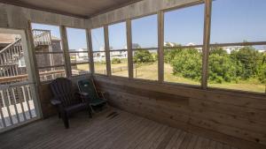 a rocking chair on a screened porch with windows at KH146, Camelot- Oceanside, Screened Porch, Close to Shopping and Restaurants! in Kitty Hawk