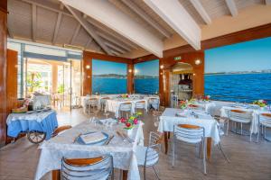a restaurant with white tables and chairs and the water at Hotel Villa Elena in Tortoreto Lido
