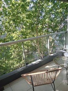einen Balkon mit einem Stuhl, einem Tisch und Bäumen in der Unterkunft Be Happy Studio Palermo Soho in Buenos Aires