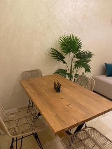 uma mesa de madeira com cadeiras e uma planta num quarto em Luxury & cosy apartment em Marrakech