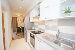 a kitchen with white cabinets and a sink at Apartmani Šulenta in Tučepi