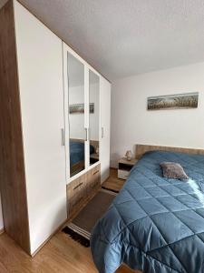 a bedroom with a blue bed and a mirror at Kamenice soba L in Jajce