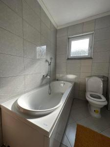a white bathroom with a tub and a toilet at Kamenice soba L in Jajce