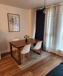 a dining room table with chairs and a vase of flowers at Appartement La Défense in Puteaux