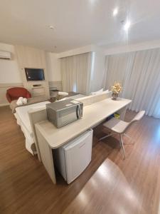 a living room with a desk with a microwave at Flat no Mercure Brasília Lider By Rei dos Flats in Brasília