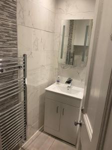 een witte badkamer met een wastafel en een spiegel bij St Margaret's Loch Apartment in Edinburgh