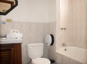 a bathroom with a toilet and a sink and a tub at Hotel Colonial in Puyo