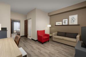 a living room with a couch and a red chair at Country Inn & Suites by Radisson, Gainesville, FL in Gainesville