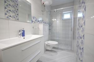 a white bathroom with a toilet and a shower at Apartmani Šulenta in Tučepi