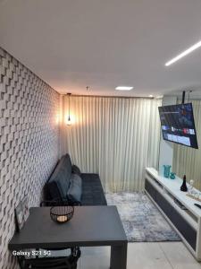 a living room with a couch and a table and a tv at Flat Luxo Jardim Goiás in Goiânia