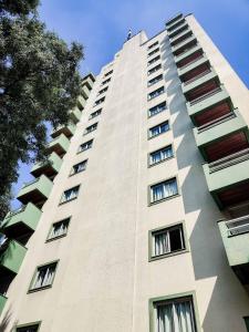 un edificio alto de color blanco con muchas ventanas en Residencial Bella Vista Suites, en São Paulo