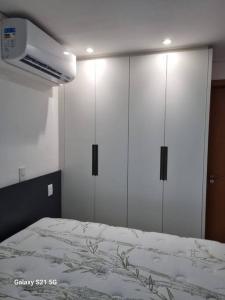 a bedroom with white cabinets and a bed at Flat Luxo Jardim Goiás in Goiânia