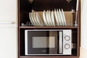 a microwave in a cabinet with plates and bowls at Studio @ Arena Națională Stadium in Bucharest