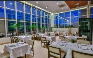 a restaurant with white tables and chairs and large windows at Jade Hotel BLUE Tree Brasília Flat Particular wi-fi e garagem grátis sem café in Brasília