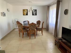 a dining room with a table and chairs and a television at Jolie Villa Santa avec piscine in Pointe aux Piments