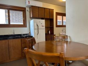 uma cozinha com uma mesa de madeira e um frigorífico branco em Apto Rua Coberta Gramado em Gramado