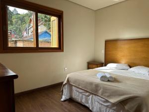 Un dormitorio con una cama grande y una ventana en Apto Rua Coberta Gramado, en Gramado