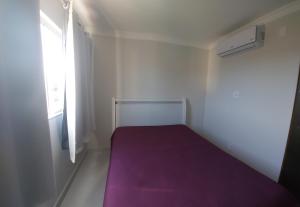 a small bedroom with a purple bed and a window at apartamento para até 5 pessoas in Vila Velha