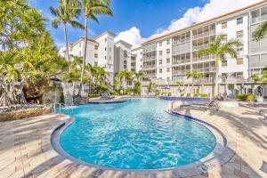 a swimming pool at a resort with palm trees and buildings at Sailor's Rest in Naples