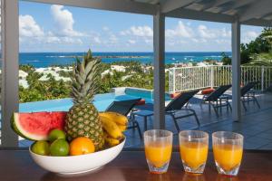 un bol de fruta en una mesa con dos vasos de zumo en Private Orient Bay Villa with Spectacular Views, en Orient Bay