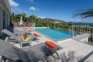 Un patio con piscina y sillas y una mesa. en Private Orient Bay Villa with Spectacular Views, en Orient Bay