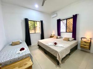 a bedroom with two beds and two windows at Villa Ometepe in Mérida