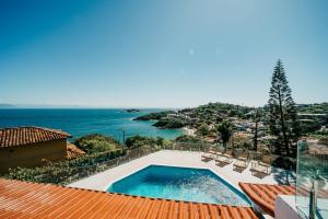 a swimming pool on top of a house with the ocean at Baía do João Eco Pousada in Búzios