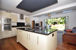 a kitchen with white cabinets and a black counter top at Lord Rod's Guest House in Staines