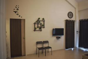 Zimmer mit 2 Stühlen, einem TV und einer Wand in der Unterkunft Mountainview Paradise in Karjat
